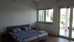 A bedroom with a bed, two bedside tables, a window, and a door leading to a balcony. - Apartment 100m from sea, with covered terrace, citrus trees (Sveti Filip i Jakov)
