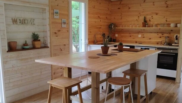 A modern kitchen with wooden walls, a central island with stools, and a welcoming 'WELCOME' sign.