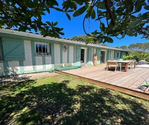 A house with a wooden deck, a covered outdoor seating area, and a small table. - Exceptional promotion for the month of September magnificent villa landaise (Messanges)
