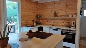 A modern kitchen with wooden paneling, a sink, a dishwasher, and a coffee maker.