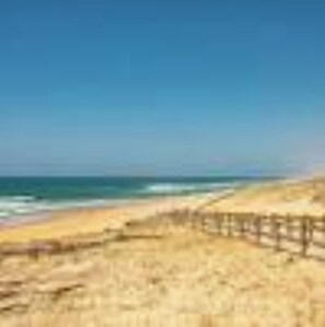 A beach with a wooden fence and a clear blue sky.