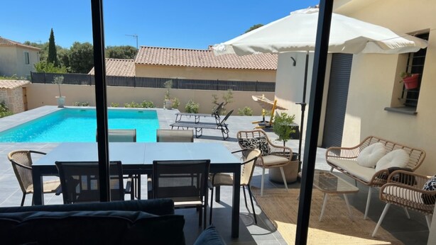 A patio with a pool, outdoor furniture, and a view of neighboring houses. - Beautiful villa in the south of France (Argilliers)