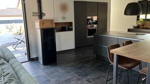 A modern kitchen with a built-in stove, dark cabinetry, and a dining area with a wooden table and chairs. - Beautiful villa in the south of France (Argilliers)