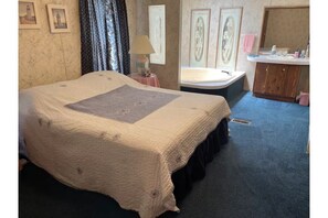 Relax in a spacious room with a large bed, wooden vanity, and framed artwork.
