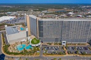 A high-rise hotel with multiple floors, a swimming pool, and a parking lot.
