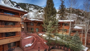 A multi-level wooden building with a pool area, outdoor seating, and snow-covered surroundings. - Fasching Haus Unit 6 | Condo with Beautiful Decor, Spacious Layout, Great Location (Aspen)
