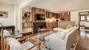 A spacious living room with a fireplace, a large sofa, and a television. - Fasching Haus Unit 6 | Condo with Beautiful Decor, Spacious Layout, Great Location (Aspen)