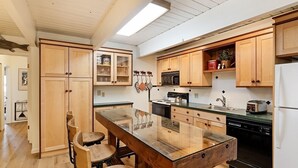 Eine Küche mit Holzausstattung, einer zentralen Kochinsel mit Sitzgelegenheiten und modernen Geräten.