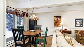 Ein Essbereich mit Holztisch und Stühlen, einer Pendelleuchte und einer Couch.
