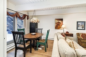Un coin repas avec une table et des chaises en bois, une lampe suspendue et un canapé.