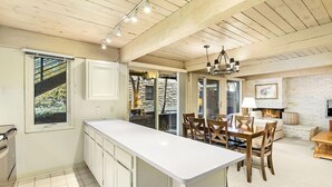 A kitchen with a long island counter, wooden cabinets, and a dining area with a table and chairs.