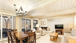 A spacious living room with a wooden dining table, sofas, and a fireplace.