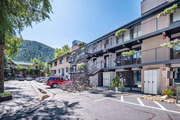 Un hôtel à plusieurs étages doté d’un parking extérieur, d’un escalier et de balcons ornés de plantes.