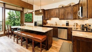 A modern kitchen with wooden cabinets, stainless steel appliances, and a large island with seating. - Durant Condominiums Unit C6 | Ski-In Condo, 2 Blocks from the Silver Queen Gondola (Aspen)
