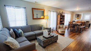 A living room with a sofa, coffee table, and dining area. - Chesapeake Chalet- Cozy,Close to Hard Rock and All (Atlantic City)