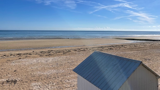 A beach with a small shed in the foreground.