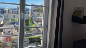 A window with a view of a town, a white door, and a sign on the wall.