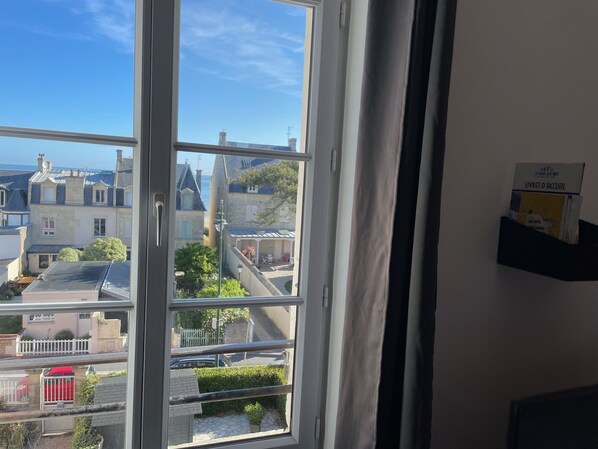 Ein Fenster mit Blick auf eine Stadt, eine weiße Tür und ein Schild an der Wand.