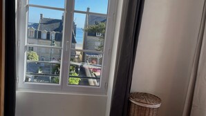 A room with a large window offering a view of buildings and a body of water.