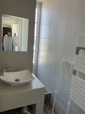 Ein Badezimmer mit weißem Waschbecken, Spiegel und gefliesten Wänden.