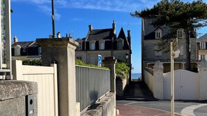A residential street with houses, a gated entrance, and a clear sky.