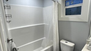 Et moderne badeværelse med badekar, toilet og et vindue med udsigt.