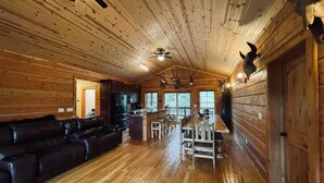 Ein geräumiges Blockhaus-Interieur mit Essbereich, Küche und einer großen Ledersofa.