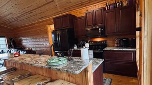 Eine rustikale Küche mit Holzschränken, einer Granitarbeitsplatte und einer Bar mit Barhocker.