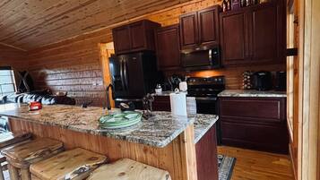 A rustic kitchen with wooden cabinets, a granite countertop, and a bar area with stools.