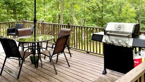 A wooden deck with a grill and outdoor furniture.