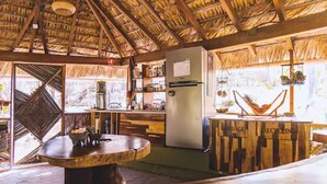 A rustic kitchen with a thatched roof, a central island, and a refrigerator. - Remote Beach Eco-Dome w/pool. Near Roca Blanca (Oax.)