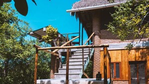 Um edifício rústico com uma escadaria que leva a um deck de madeira.
