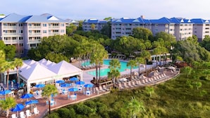 Un resort con diversi edifici, una piscina centrale, aree salotto all'aperto e rigogliosa vegetazione.