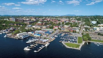 Vue aérienne d’une marina avec des bateaux amarrés, un grand ensemble d’immeubles et une végétation luxuriante environnante.