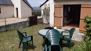 Une terrasse avec une table et des chaises, une porte en bois et une vue sur la mer.