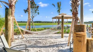 A beach area with hammocks, a wooden gazebo, and a view of a lake. - *Amazing 4Bdr TH*15mins to Disney*Free Amenities! (Kissimmee)