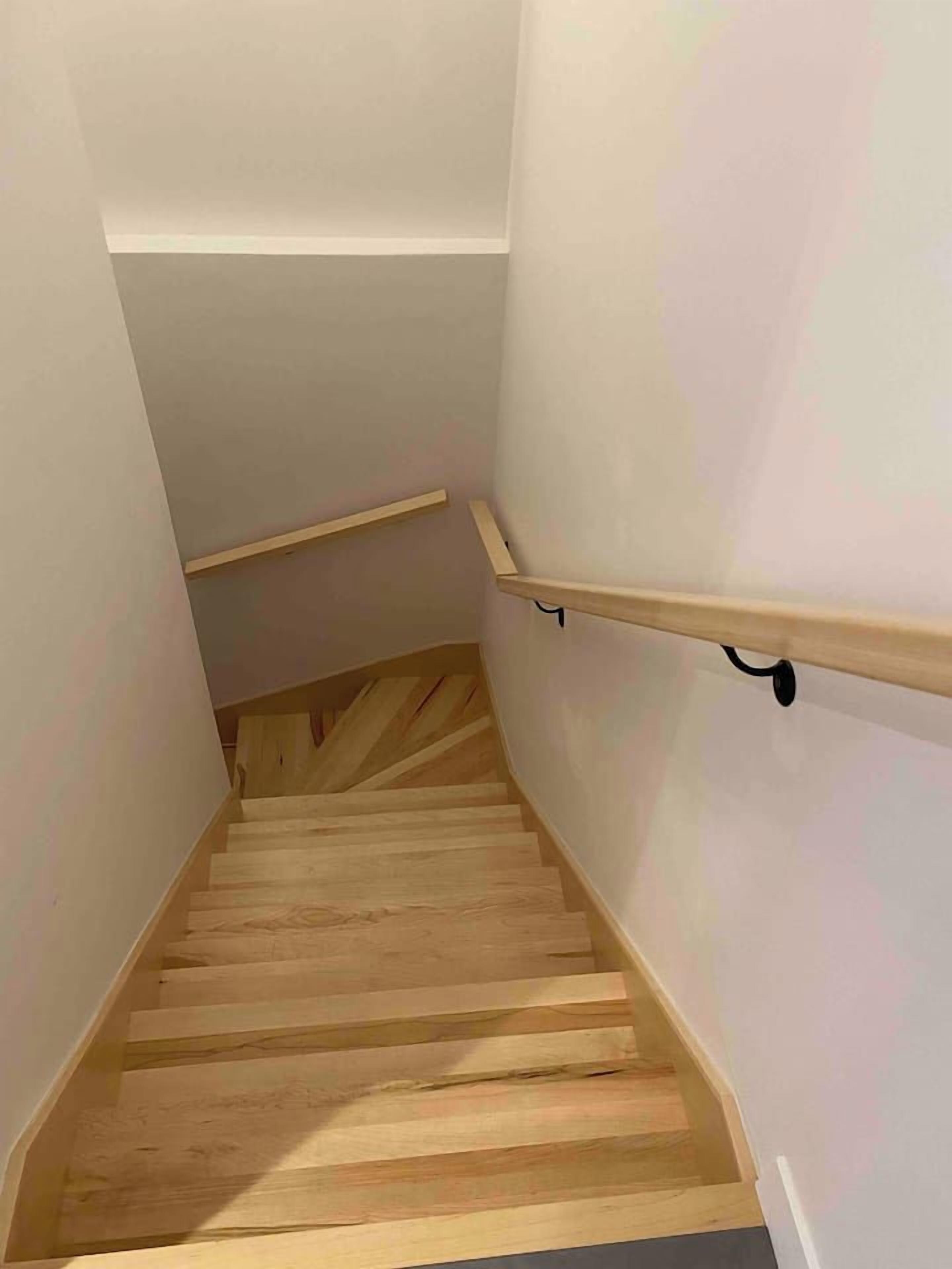 A wooden staircase with a handrail and a light-colored wall.