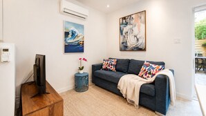 A modern living room with a grey sofa, colorful cushions, a mounted TV, and abstract art on the walls. - Perfect 2bdr in the hart of Montreal (Montréal)