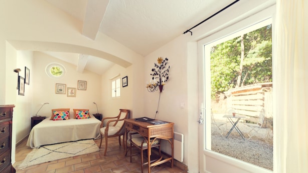 Ein Schlafzimmer mit einem Bett, einem Schreibtisch, einem Stuhl und einem Fenster.