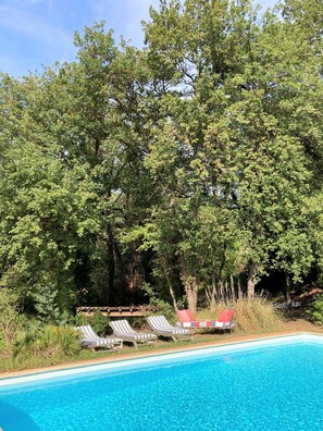 Una piscina con sillas de descanso y una terraza de madera.