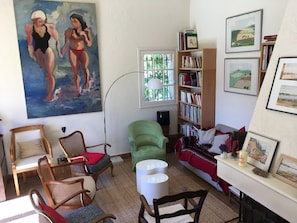 Una sala de estar con un cuadro grande, una estantería y un sofá.