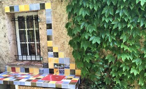 A bathroom with a tiled sink and a window with a metal gate.