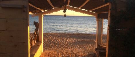 A wooden beach hut with a sign reading "LA PLAGE" and a view of the beach and sea.