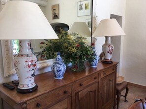A wooden dresser with two ornate lamps, a mirror, and a vase with yellow flowers.