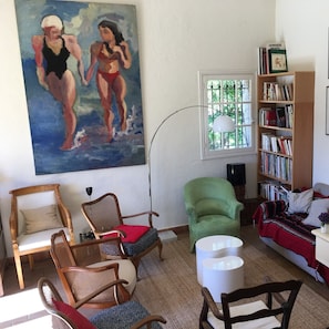 Ein Wohnzimmer mit einem großen Gemälde, einer Bücherwand und mehreren Sesseln.