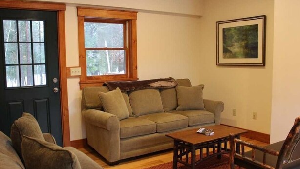 A living room with a sofa, a coffee table, and a chair. - Large Log Cabin in the Heart of the ADKS (Keene)
