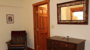 Una stanza con una porta in legno, un comò in legno scuro e uno specchio con cornice appeso al muro.