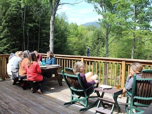 A wooden deck with outdoor seating and a view of a forested area.