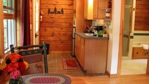 Un interior de madera con cocina, una mesa de comedor con sillas y una pequeña alfombra.