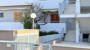 Un edificio a più piani con ingresso recintato, una scala e un balcone.